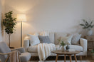 "Cozy small living room with a light sofa, layered cushions, wooden coffee table, floor lamp, and green plants, styled in Scandinavian design to maximize limited space.