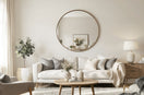 A bright modern living room with a large round wall mirror above a beige sofa, wooden coffee table, soft neutral tones, Scandinavian interior style.